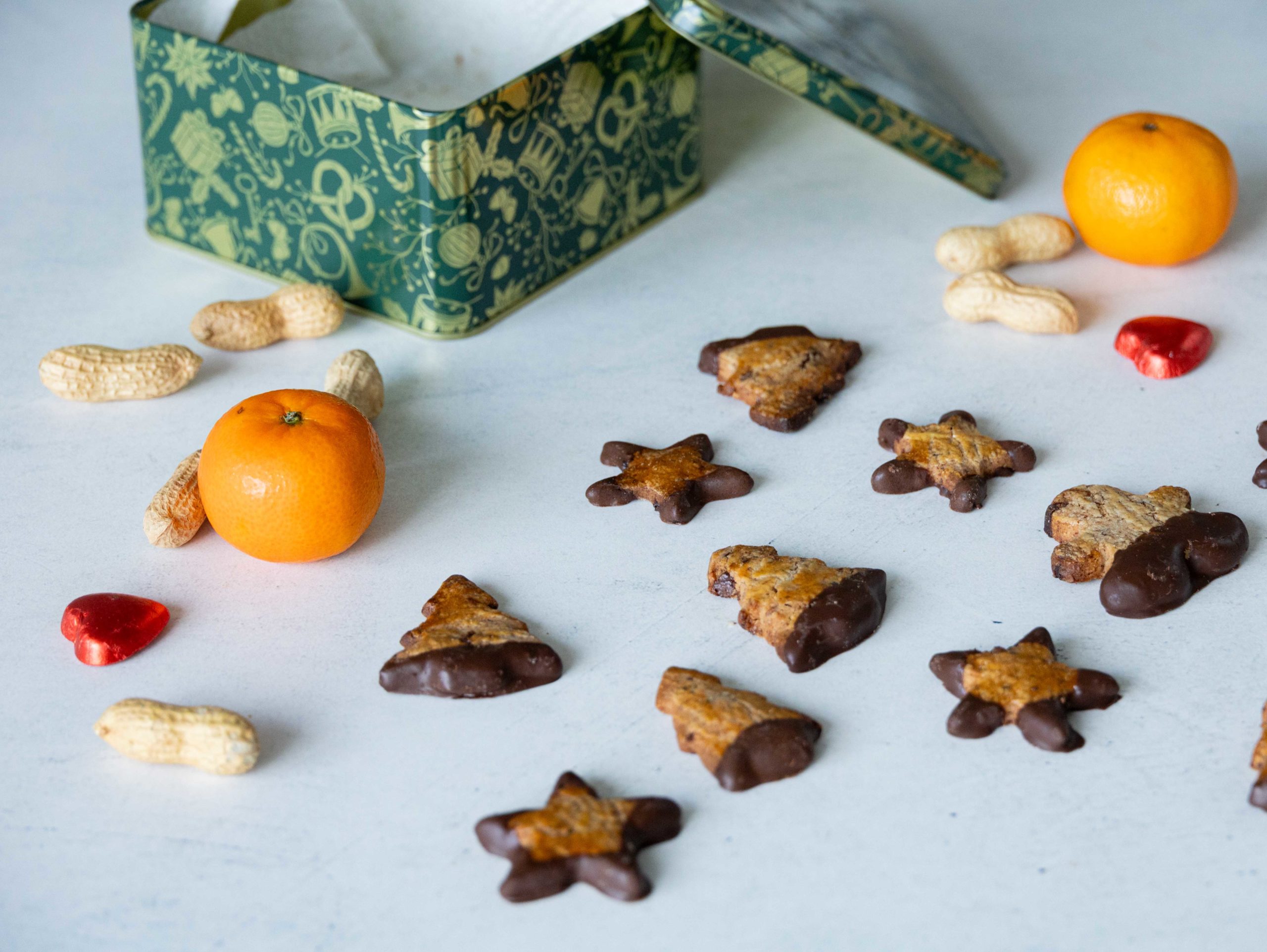 Stracciatelle Guetzli auf einem Tisch mit einer Guetzlibox, Manderinli und Erdnüssen