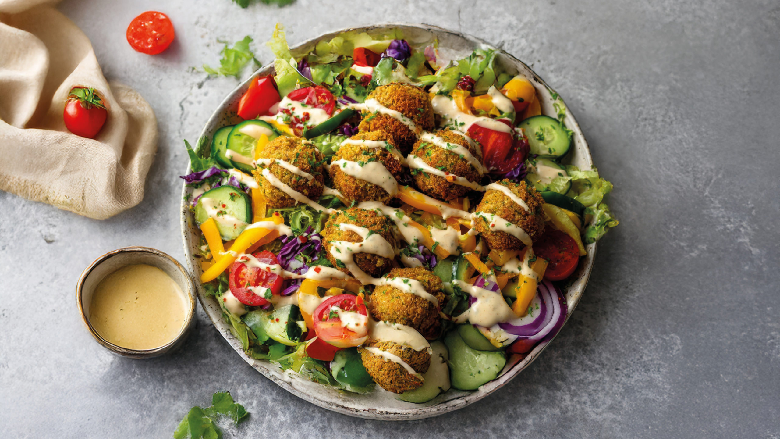 Orientalischer Falafel-Salat mit leckerem Dressing auf einer grauen Arbeitsplatte