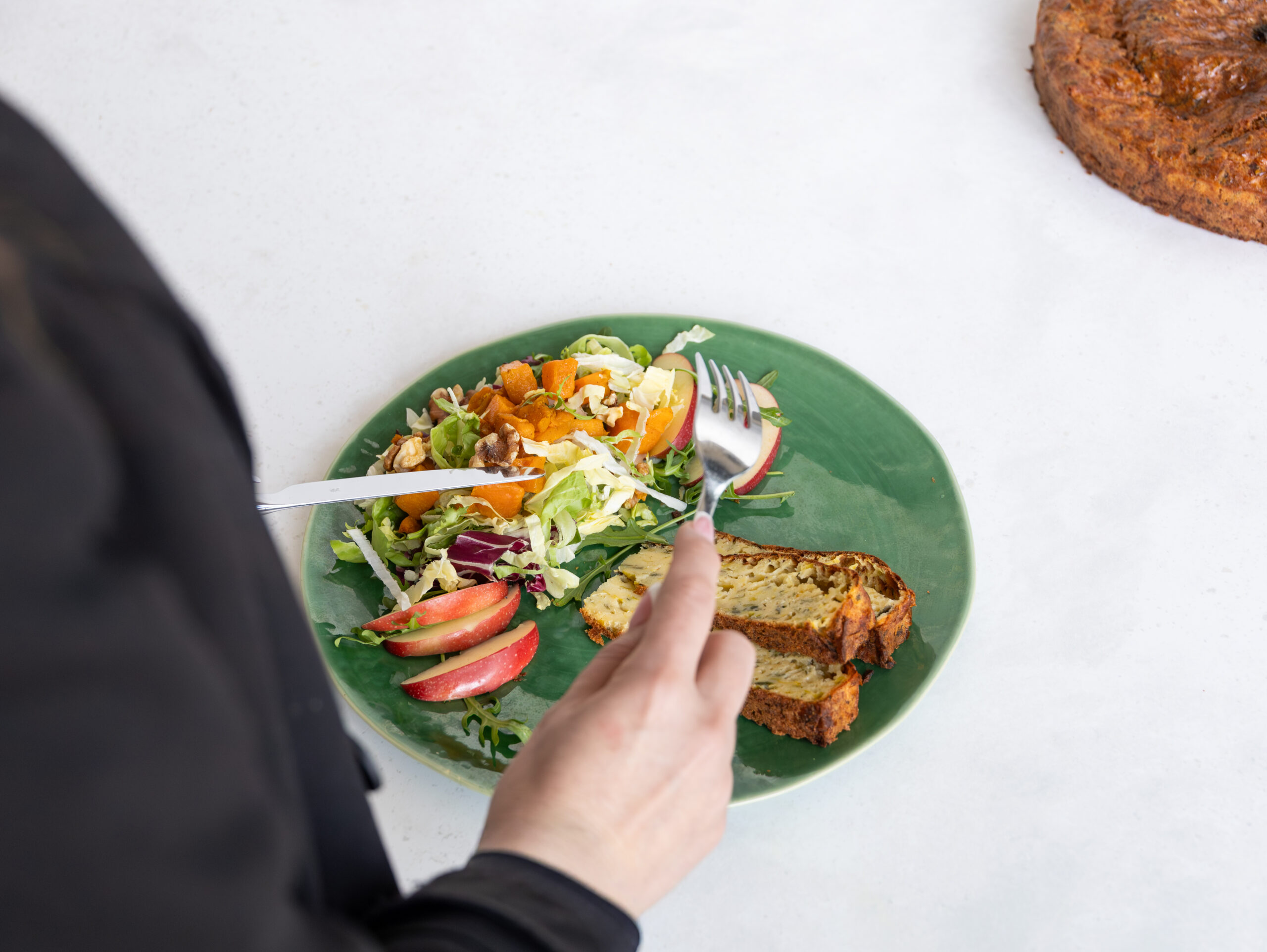 Lauchkuchen mit Alpkäsen und knackigem Salat mit drei Apfelscheibchen auf einem grünen Teller
